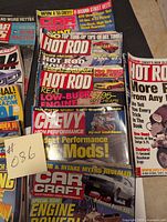 Photo showing several car magazines stacked together, prominently featuring Hot Rod, Chevy High Performance, Car Craft titles with colorful covers and performance tips
