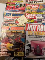 Close-up image showing various Popular Hot Rodding and Hot Rod magazine covers featuring muscle cars and engine tuning topics.