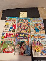 Photo showing all six Archie comics laid out on a surface with a black backdrop and a number card.