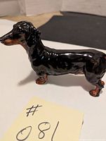 Side view showing glossy black and brown detailed dachshund figurine posed standing, 6" long, 4" high.