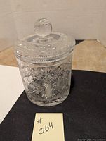 Front view of the crystal ice bucket with lid on a black surface and tan tiled background.