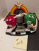 Front view showing red and green M&M figures and jukebox dispenser with checkered base.