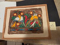 Full view of the framed indigenous folk art painting featuring colorful birds and flowers.