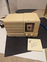 Front and left side view of beige RCA Victor Little Nipper radio with tuning dial and two knobs on the front.