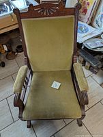 Top front view of the antique green rocking chair showing the carved wooden backrest and green upholstered seat and armrests.