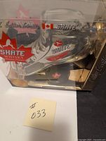 Front view of the skate-shaped glass bottle with Skate Whisky branding inside original clear plastic display packaging.