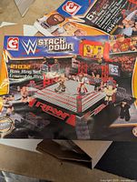 Box showing WWE Stack Down Raw Ring Set with wrestling figures and accessories, highlighting the assembled ring in action.
