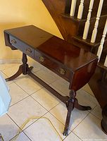 Front view of the wooden entry table showing two drawers, polished top and carved legs.