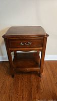 Front view of antique solid wood bedside table showing drawer and shelf.