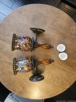 Top view of the two mosaic candle holders and two white egg cups on a wooden table.