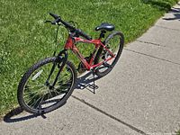 Full side view of the red Huffy Granite bike on pavement and grass, showing overall condition and components.