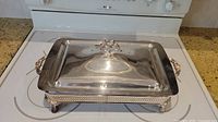Silver colored buffet chafing dish with decorative lid and handles shown from top angle.