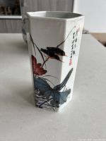 Hexagonal faux porcelain vase showing bird sitting on a branch with flowers and calligraphy art, close-up side view