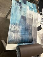 Two fabric roll mats on table; one in abstract blue-gray pattern, one solid brown.
