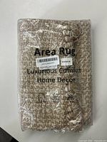 Packaged beige area rug showing text with dimensions and care instructions.
