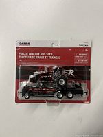 Front view of the Case IH Red Rumbler puller tractor and sled toy in original blister packaging showing product details and branding.