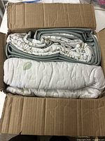 Photo showing the folded floral patterned quilted blanket inside a cardboard box, highlighting the visible quilt stitching and green leaf print.