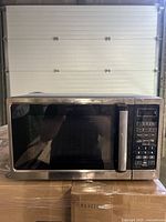 Front view of stainless steel Insignia microwave oven with glass door and control panel.