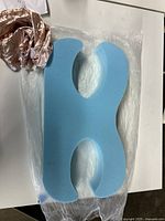 Top view of blue memory foam cushion with pink satin cover removed and placed beside it, showing cushion shape and texture.