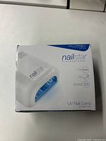 Front view of the NailStar Professional NS-01 UV Nail Lamp box in white and blue with product image and specifications.