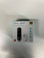 Front of the box showing TP-Link Kasa Smart Doorbell with 2K resolution, icons for features including WiFi, night vision, IP65 weather resistance, and app control.