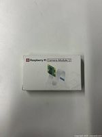 Front view of original Raspberry Pi Camera Module 2 box showing branding and image of camera module.