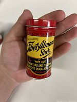 Front view of red metal tin container showing product name and purpose.