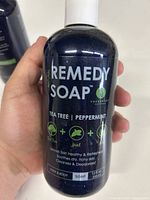 Front of a 12 fl oz (356 ml) dark blue bottle of TruRemedy Naturals body soap with label showing tea tree and peppermint essential oils.