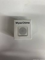 Front view of a white Wyze Chime wireless doorbell chime with speaker grille and Wyze Chime text