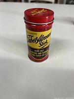 Front view of the red metal tin showing the product name 'The Amazing Tibet Almond Stick' with claims about wiping out furniture and floor scratches.