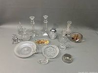 Full view of clear glass collection including candlesticks, cruets, lighter, paperweights, and bowls