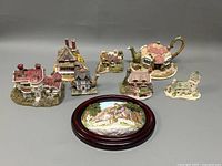 All miniature cottages, the cottage teapot, and decorative stone plaque displayed on a flat surface showing the variety of items.