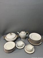 Full set view showing chocolate pot, tureen, stacked plates, gravy boats, and creamer with gold trim details