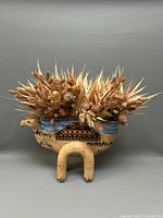 Front view of large camel pottery planter with dried flowers in belly section.
