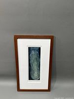 Full view of the framed copper block abstract etching showing the wooden frame and white mat surrounding the blue-green abstract design.