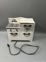 Full view of the Empire electric toy stove with stovetop, control knobs, oven doors, and attached power cord.