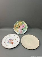 Three charger plates displayed, showing floral designs and embossed detail