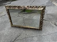 Photo showing the ornate gilt rectangular wall hanging mirror with detailed scroll and floral design on the frame.
