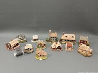 Twelve Liliput miniature cottage homes arranged in a group showing various styles and materials.