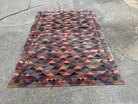 Full view of rug laid flat on pavement showing overall pattern and condition