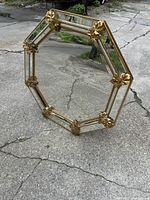 Front view of the octagonal wall mirror showing the full ornate grape and vine frame and the mirror surface.