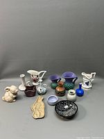 Overview of collection of pottery and ceramic items arranged on grey surface, showing all pieces