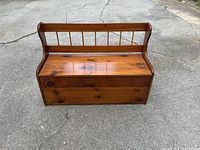 Full view of vintage wooden storage bench showing front, backrest with vertical spindles, and lift-up seat closed