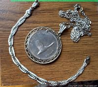 Necklace pendant with coin and bracelet laid on wooden surface