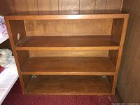 Frontal view of the wood veneer bookcase with three shelves, showing open shelves and wood finish.