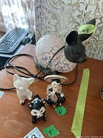 Photo showing metal and glass bunny lamp with three small ceramic figurines on a wooden surface.