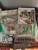 Top view of the costume jewelry lot showing multiple boxes with assorted necklaces, brooches, earrings, and bracelet pieces.