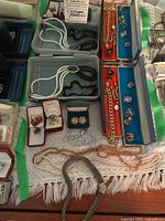 Overhead view of assorted costume jewelry laid out including necklaces, rings, bracelets, chokers in jewelry boxes and trays