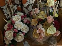 Two bouquets of artificial flowers with different colors and types, placed against a floral curtain background.