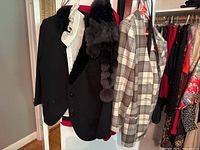 Three blazers hanging on a rack, includes black, checked and red garments, showing the styles and colors of blazers.